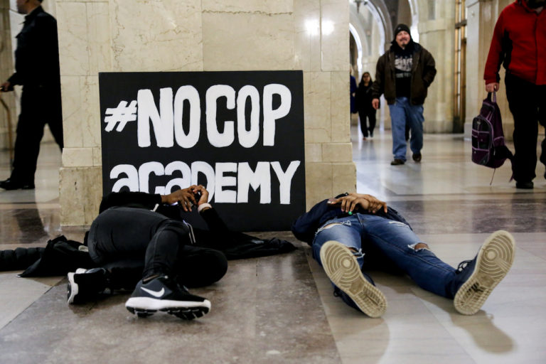 Young activists participating in a die-in at a #NoCopAcademy protest at City Hall