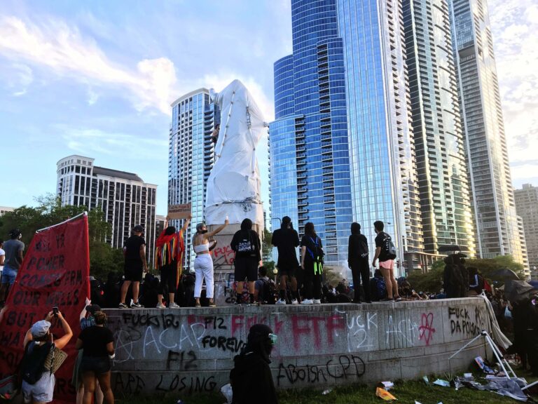 Protestors standing in front of the Christopher Columbus statue in Grant Park during the Decolonize Zhigaagoong protest | Photo by Parsons