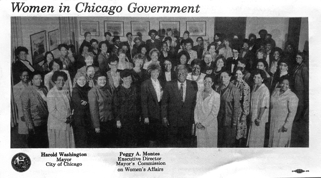 Mayor Harold Washington is standing in a group photo with the women he appointed to be on his staff. During his term, 175 women were appointed to boards and commissions by Mayor Washington.