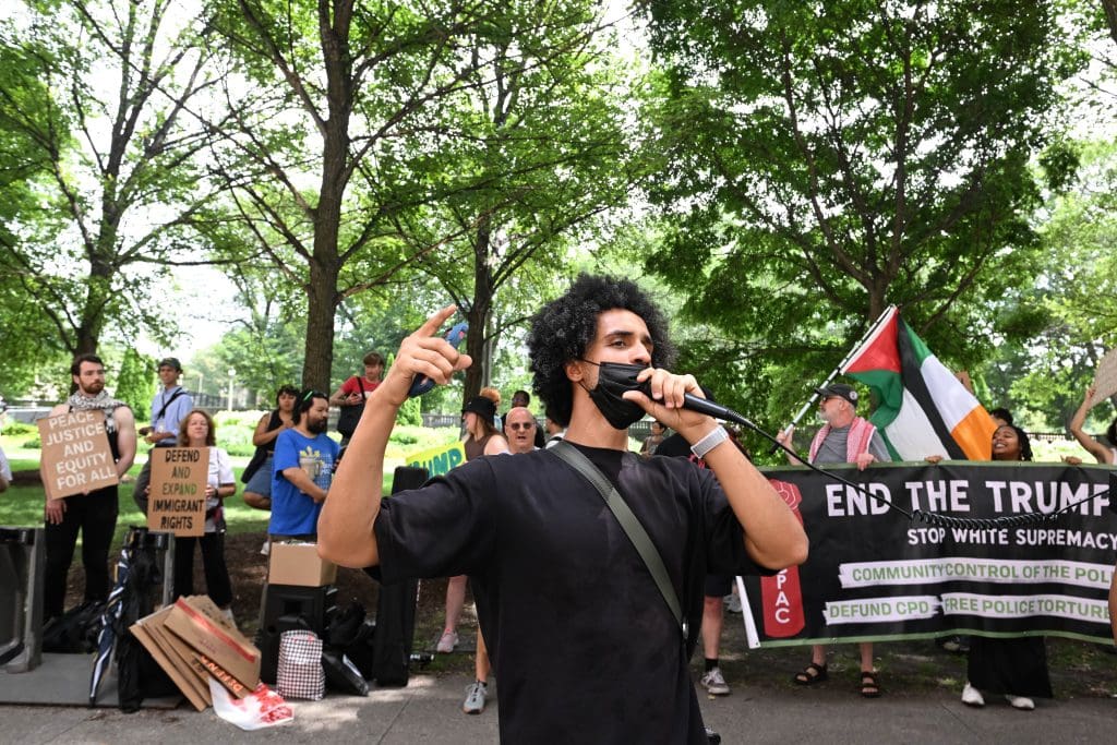 Merawi Gerima, a community organizer with CAAPR, led protesters in chants to protest Donald Trump speaking at The National Association of Black Journalists (NABJ) in downtown Chicago on July 31, 2024. Photo by Alexander Gouletas for The TRiiBE®