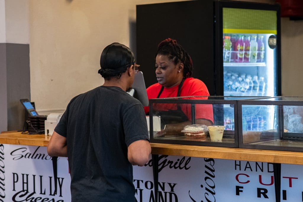 An employee at Retro Grill, located at 8126 South Stony Island Avenue, serves a customer. Photo by Ash Lane for The TRiiBE®